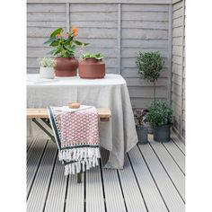 two potted plants sit on top of a wooden bench next to a white table