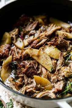 a pot filled with meat and potatoes on top of a table