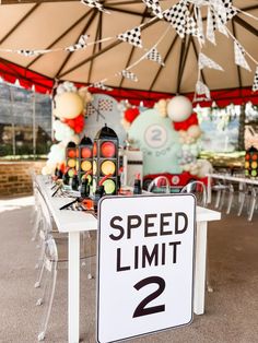 a speed limit sign sitting on top of a white table under a large tent covered in balloons