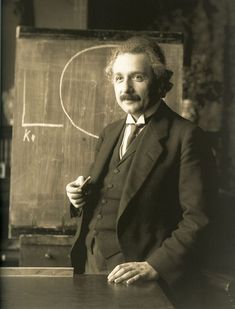 an old photo of a man standing in front of a blackboard