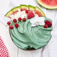 a cupcake topped with green frosting and fresh berries next to a slice of watermelon