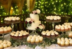 a table topped with lots of cupcakes covered in white frosting and flowers