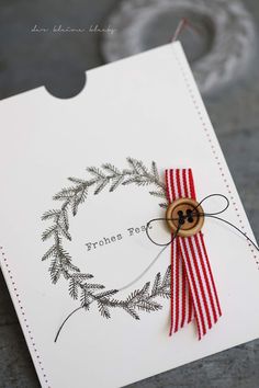 a close up of a greeting card with a button on the front and red ribbon