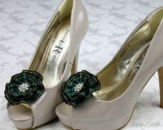 a pair of white high heel shoes with a green flower on the front and side