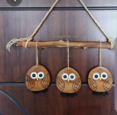 three wooden owls are hanging from a branch