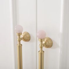 the door handle is gold and has two pink glass knobs on each side of it