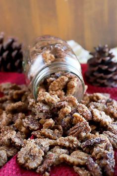 a glass jar filled with food sitting on top of a red cloth next to pine cones