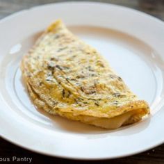 an omelet on a white plate sitting on a wooden table