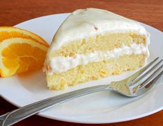 a slice of cake with white frosting and orange slices on a plate next to a fork