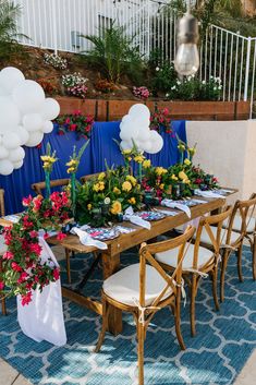 a table set up with flowers and balloons