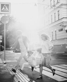 black and white photograph of three people running across the street in front of a crosswalk