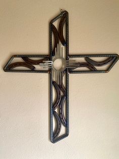 a metal cross hanging on the side of a wall next to a brown and white wall