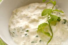 a white bowl filled with some type of food on top of a green table cloth