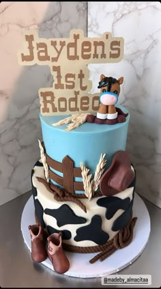 a blue and white cake with a cow on it's top that says jayden's last rodeo