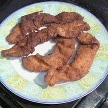 chicken strips on a plate sitting on the grill