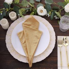 a place setting with gold napkins and flowers