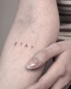 a woman's arm with the word stay tattooed on her left side, in black ink