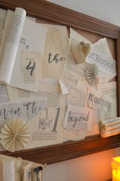 an old book page is displayed on the wall next to a candle and some books