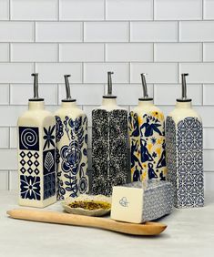 four different types of soap dispensers on top of a counter next to a wooden spoon