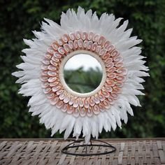 a white flower shaped mirror sitting on top of a wooden table next to a tree