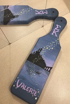 two wooden paddles with the words valerie painted on them sitting on a tile floor