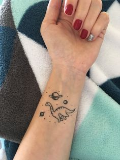 a woman's arm with a small dinosaur tattoo on it