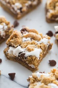 chocolate chip cookie bars with marshmallow toppings on a white surface and scattered chocolate chips