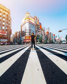 a person standing in the middle of a crosswalk on a city street with tall buildings