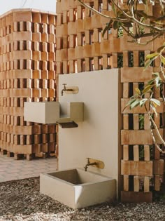 a water fountain in front of a wall made out of wooden pallets and bricks