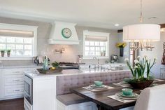 a kitchen and dining room area with white cabinets, counter tops, and table in the center