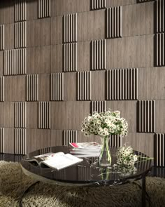 a glass table with flowers on it in front of a wall made out of wooden planks