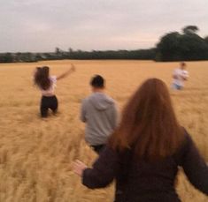 three people in a field flying a kite with their arms spread out to the side