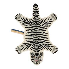 a zebra rug with a pencil sticking out of it's mouth and an animal head on the floor