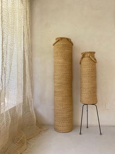 two large round baskets sitting next to each other in front of a curtained window