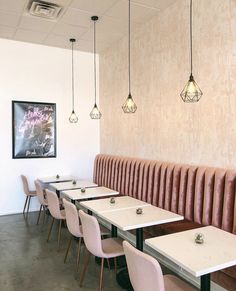 an empty restaurant with tables and chairs lined up against the wall, along with hanging lights