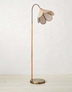 a wooden floor lamp with a metal base and flower shaped shade on the light bulb