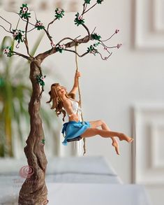 a figurine is sitting on a swing in the air next to a tree