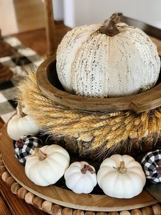 a white pumpkin sitting on top of a wooden bowl filled with hay and other fall decorations