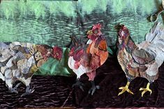 two roosters are standing next to each other on a table cloth covered with fabric