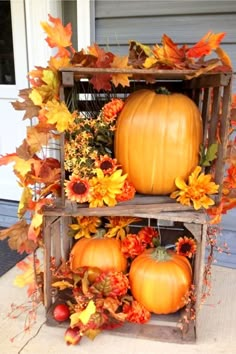 two wooden crates filled with pumpkins and autumn leaves on the front porch in fall