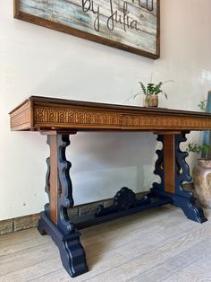 a wooden table sitting on top of a hard wood floor next to a planter