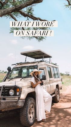 a woman sitting on the back of a white suv under a tree with an awning over her head