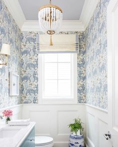 a white toilet sitting next to a window in a bathroom under a chandelier