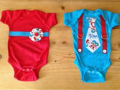 two baby onesuits with ties on them sitting next to each other in front of a wooden floor