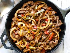 a skillet filled with beef, peppers and onions