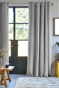 a living room scene with focus on the drapes and table in front of the window