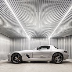 a white sports car is parked in a room with corrugated walls and flooring on the ceiling