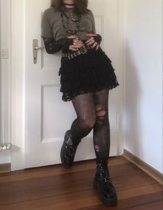 A mid-sized person/girl wearing a dark green graphic shirt, a black ripped tights top, a black mini skirt, patterned tights, a belt, black platform dr. Martens and multiple crystal rings and bracelets. 		The person is also wearing multiple silver necklaces, a big one in form of a cross. Alt Doc Martens Outfit, Slvt Aesthetic, Crowcore Fashion, Gremlincore Outfits, Crowcore Outfit, Fit Aesthetic Outfit, Platform Doc Martens Outfit, Grunge Goth Outfits, Doc Martens Outfit Grunge