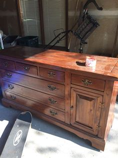 a large wooden dresser sitting in the middle of a room next to a skateboard