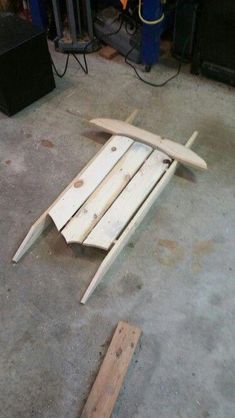 a wooden surfboard laying on the ground next to some wood planks and tools